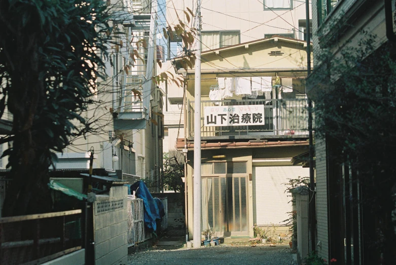 a narrow, empty street with a house and shop in the distance