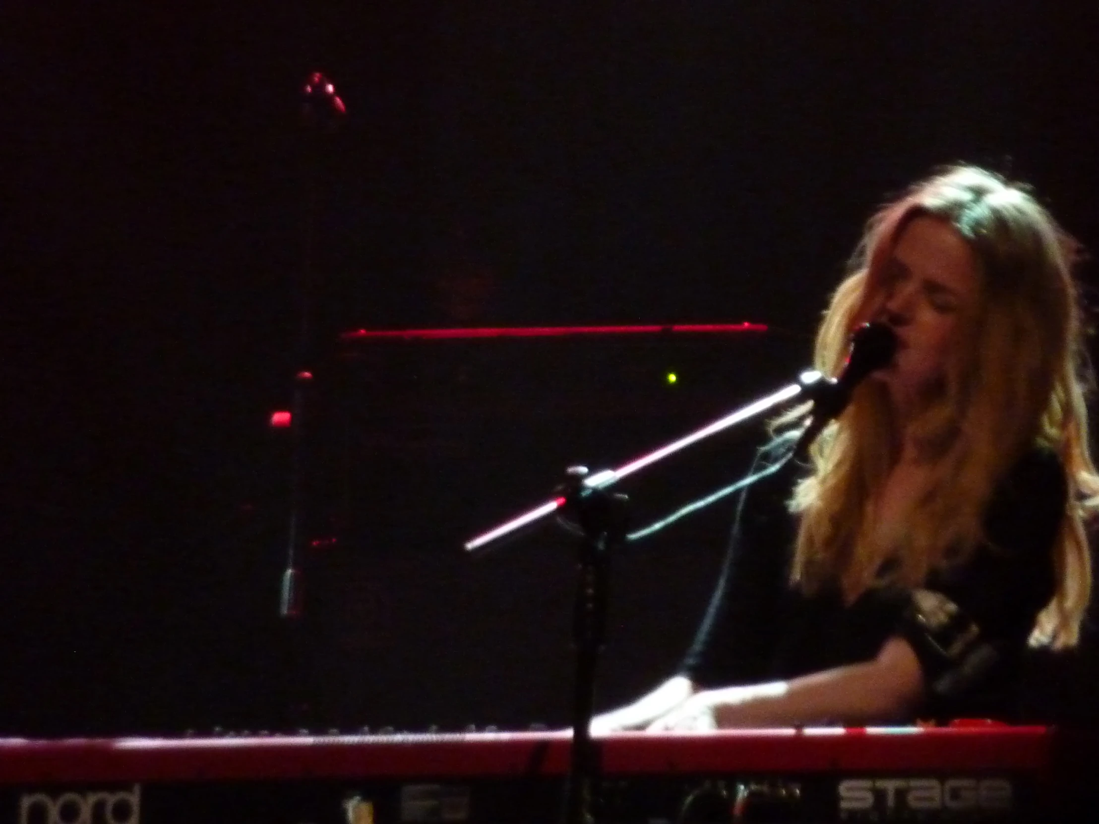 a woman is singing in front of microphones on a keyboard