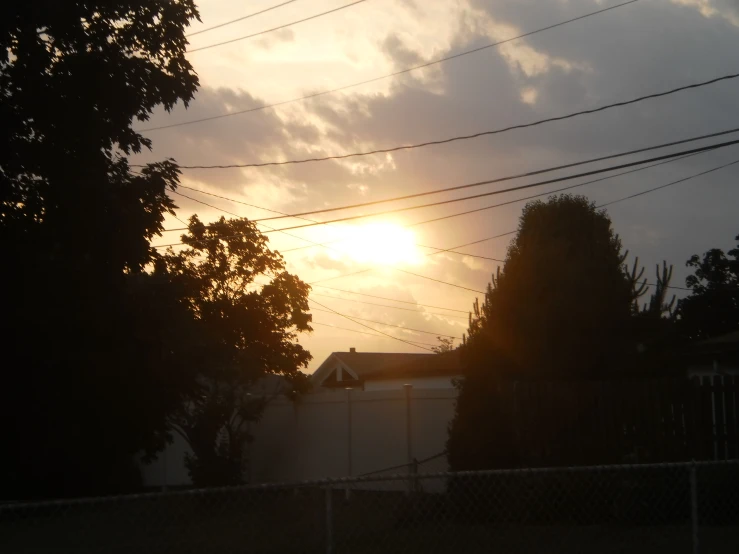 the sun is setting over a fenced area