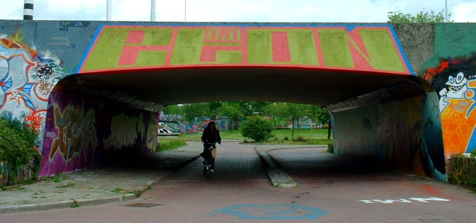 person riding their bike through a graffiti covered bridge