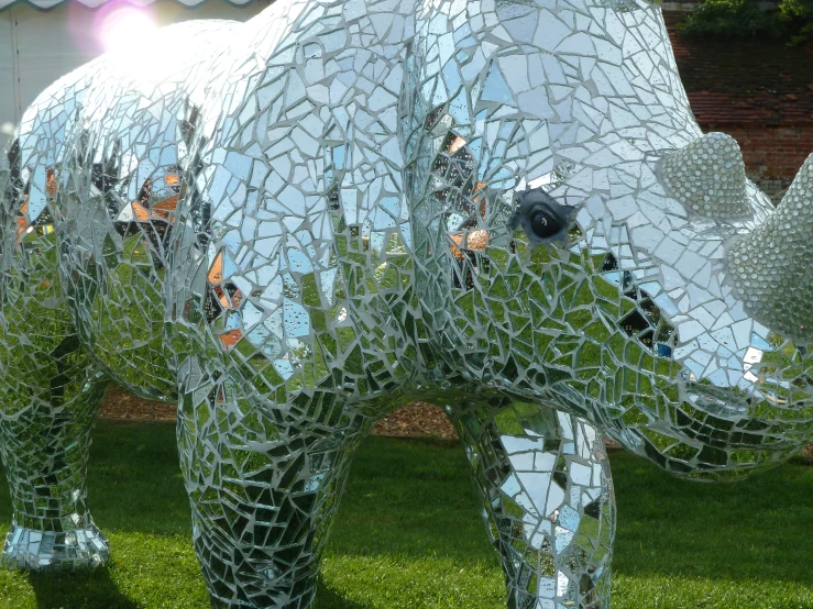 two sculptures of rhinos made out of many broken pieces