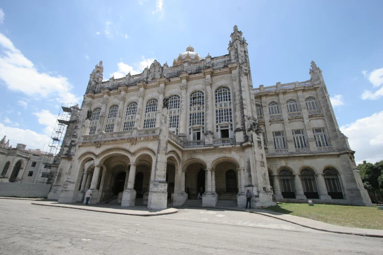 a large building with pillars and windows near grass