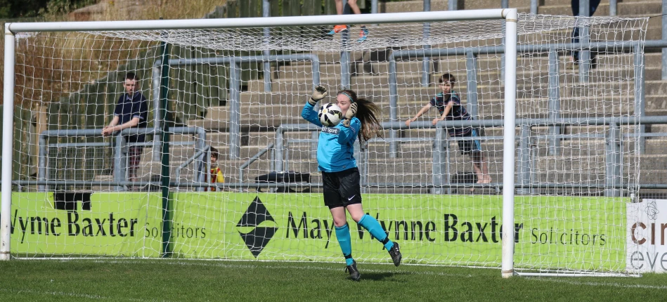 the female player is in the goalie box jumping up and catching the ball