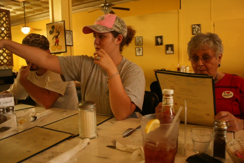 three people sitting at a table while holding some food