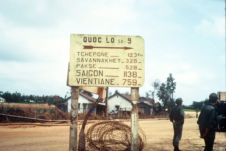 two men are standing in the dirt near a sign