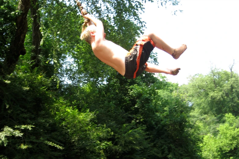 a person doing a flip in the air next to a forest