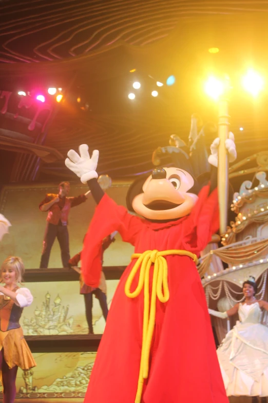 the man in a red costume and other actors performing on stage