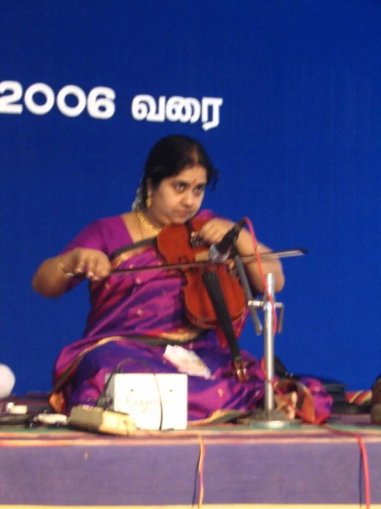 a lady is sitting on a stage playing an instrument