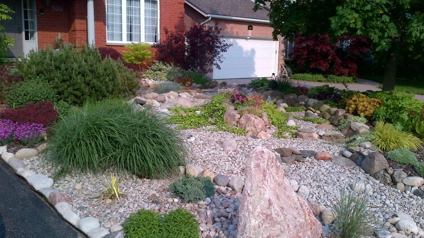 some rocks a house and trees and some flowers