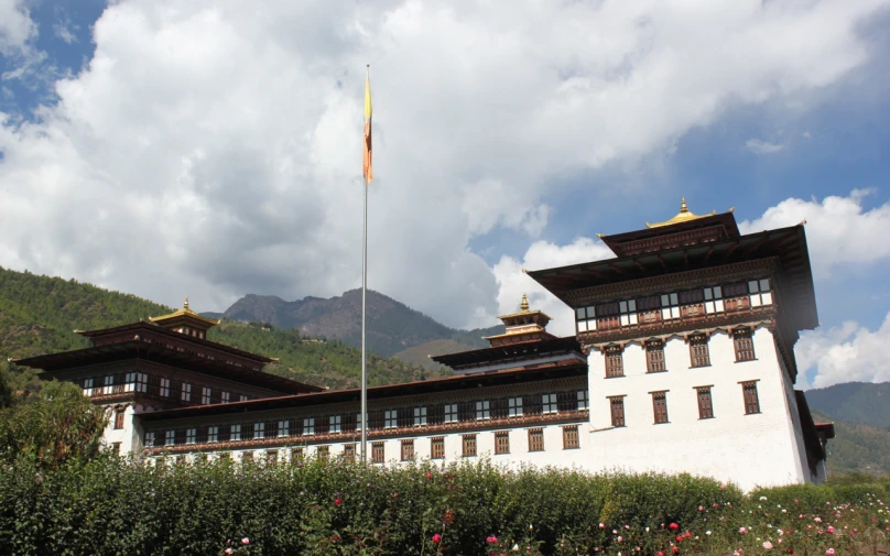 there is a large white building and some mountains in the background