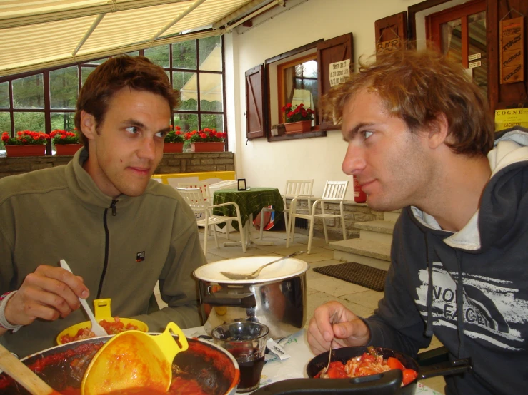 two men are sitting at a table with food