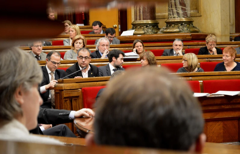 several people sitting in the rows of wooden chairs