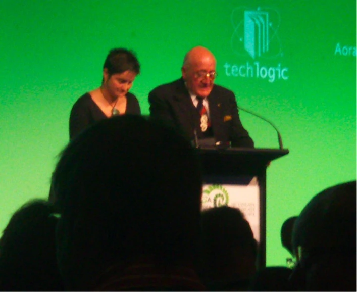 two people speaking on a stage together at a podium