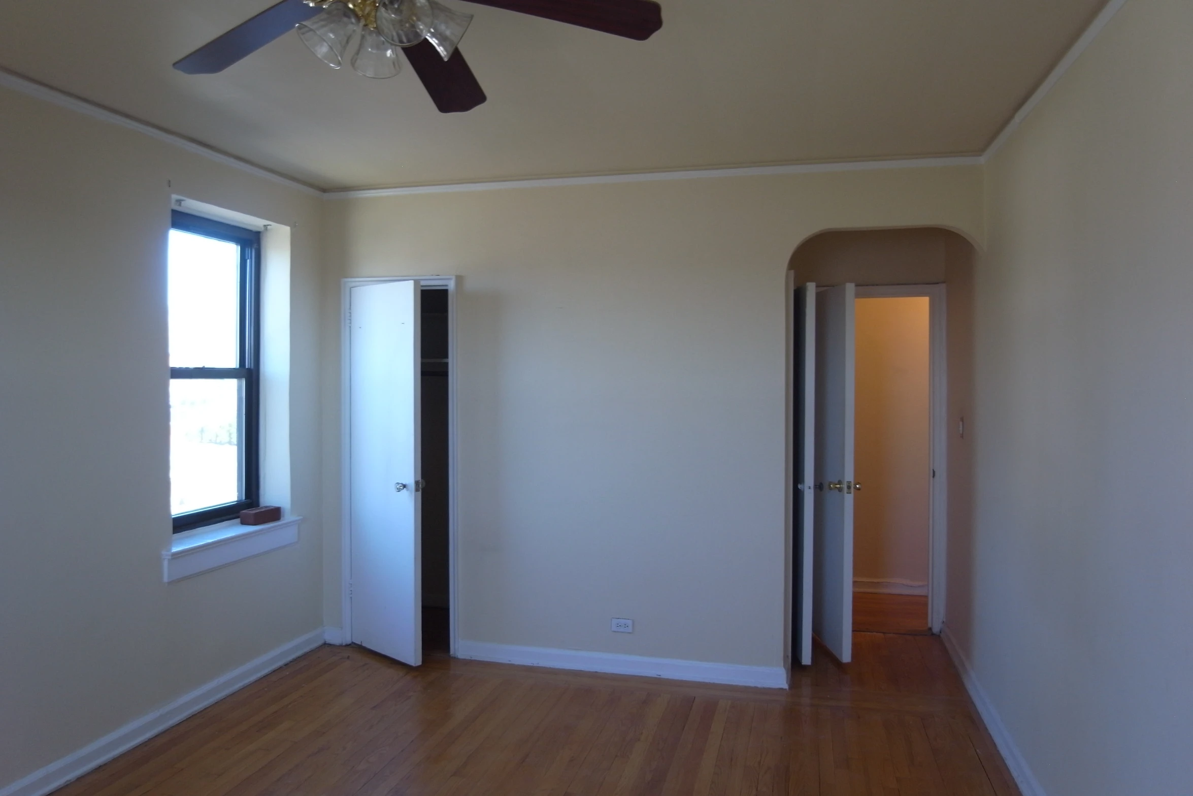 empty living room with ceiling fan, hardwood floors, and open door