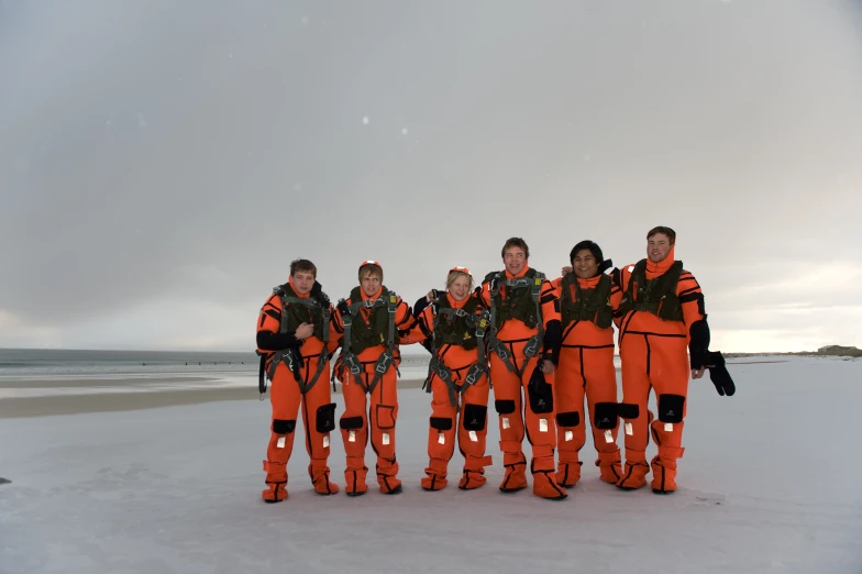 several people standing on the beach in diving gear