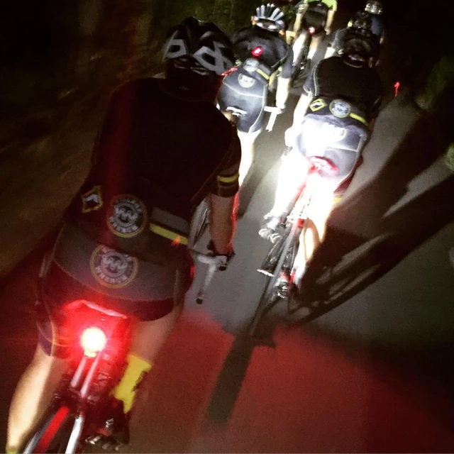 a line of cyclists wearing helmets wait at a red light