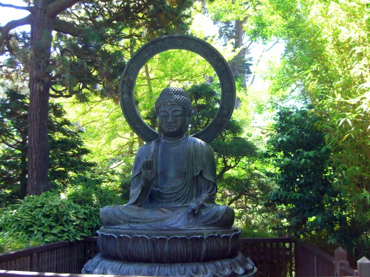 a statue sitting inside of a lush green park