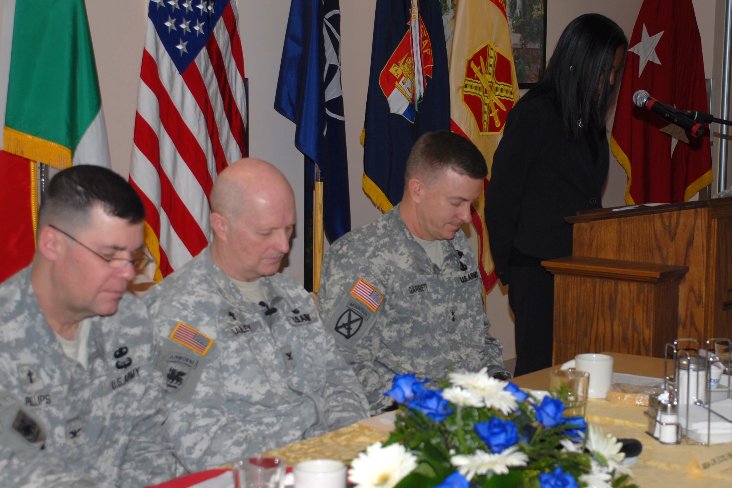 three men in uniforms are sitting at a table with two men talking