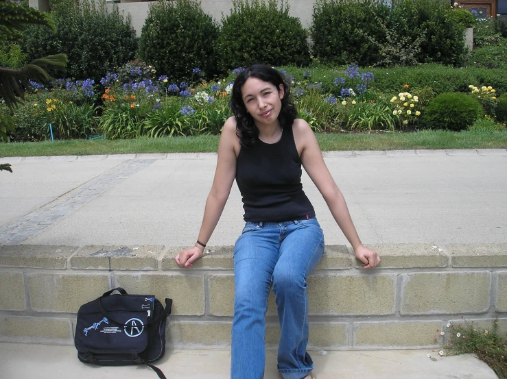 a girl sitting by the side of a sidewalk smiling