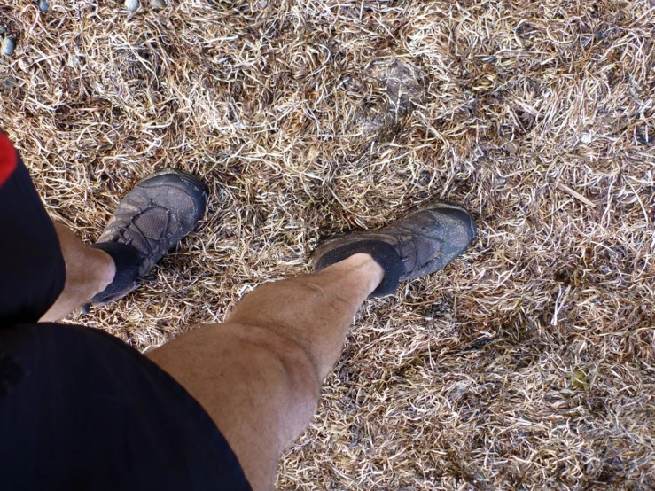 view of legs with no shoes standing in the dirt