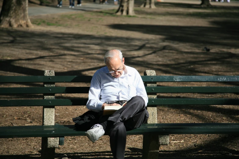 an old man sitting on a bench reading a book