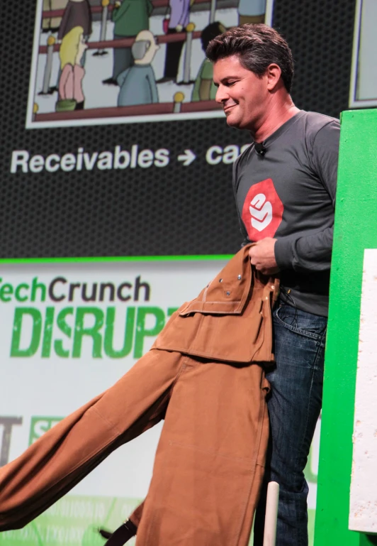 a man is in front of a green wall holding onto a coat