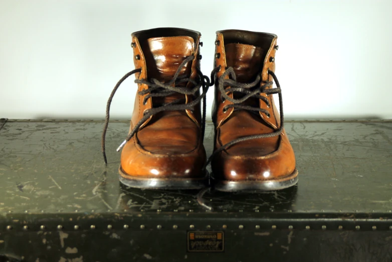 worn boots are sitting on top of a black suitcase