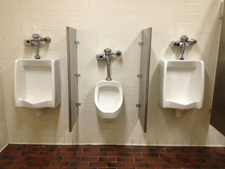 a bathroom with three urinals and three hand rails