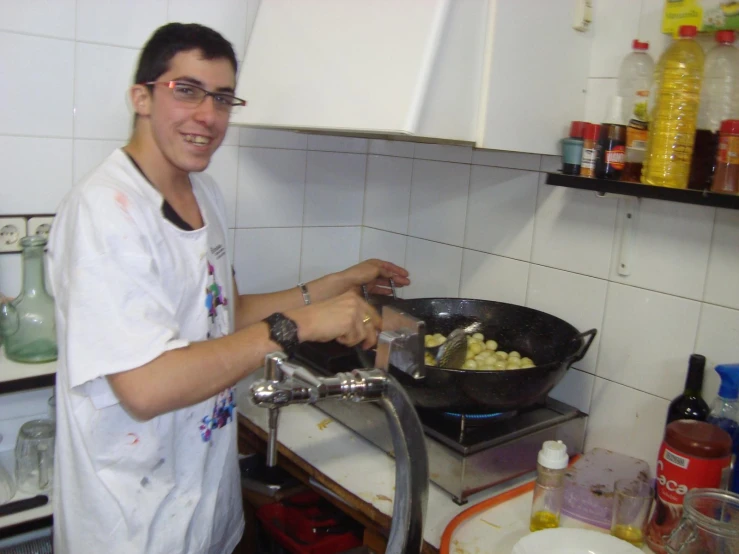 a man in the kitchen frying food on a pan