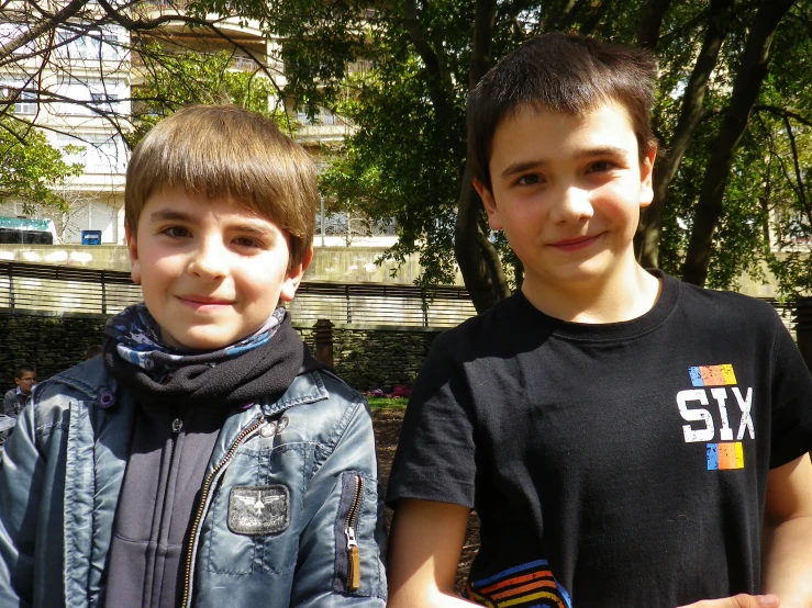 there are two boys standing together by some trees