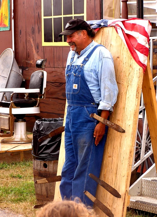 man in an overalls with a flag on top of wooden structure