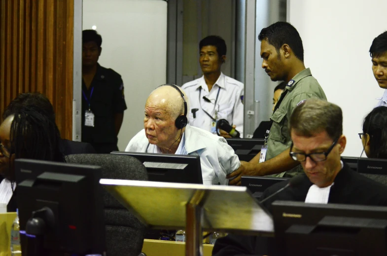 men in military uniforms and white shirts look at computers