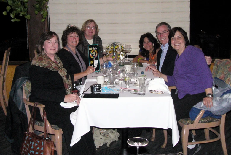 a group of people sitting around a table with a white table cloth