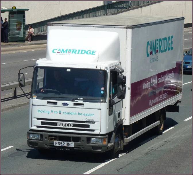 a delivery truck driving down the road with the word cambridge on it