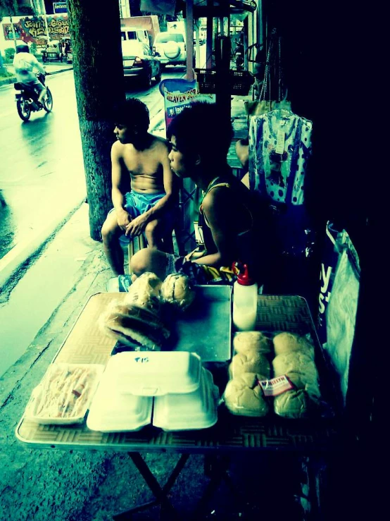 two children eating at an outdoor table on the street