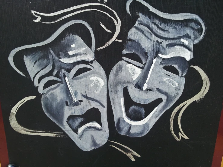 two painted masks on a black canvas with the faces of two men