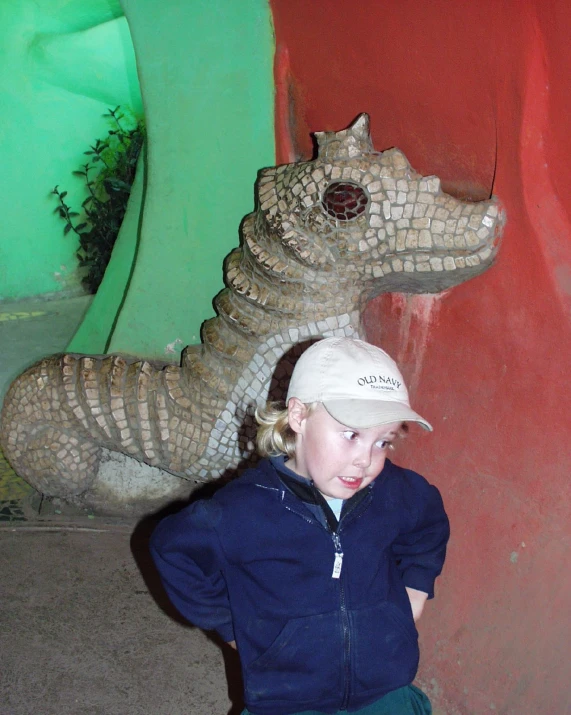 there is a girl in a hat near a crocodile