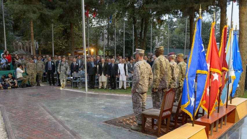 men in uniforms standing at a podium with flags