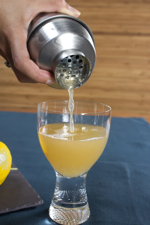 person pouring juice into a drink glass on a blue table cloth