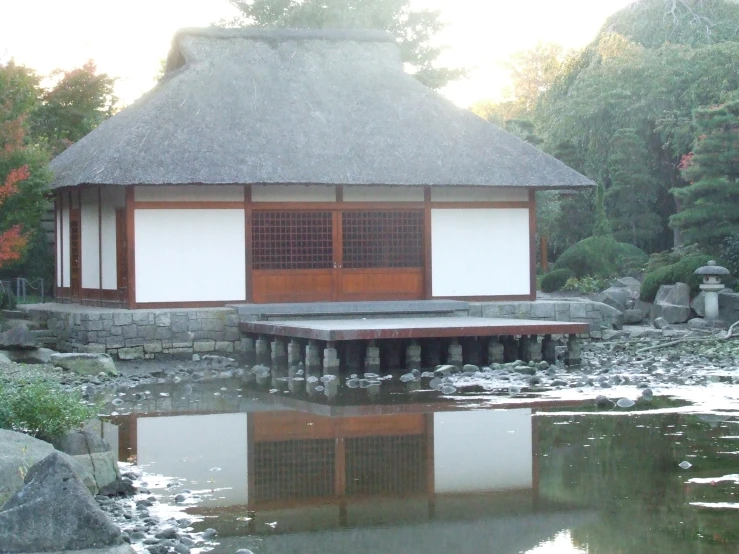 an asian style pavilion is reflecting in water