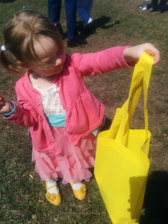 a little girl holding a yellow plastic bag