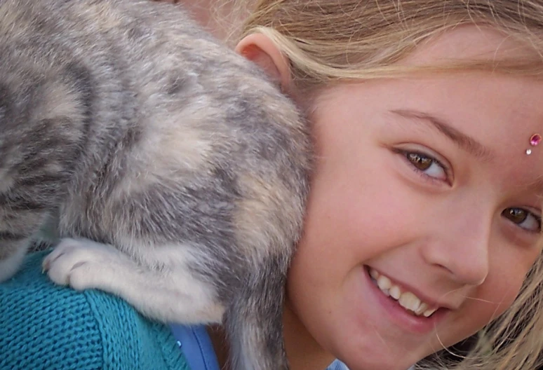 a girl holding a cat with a smile on her face