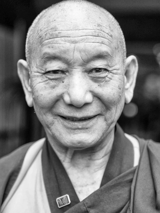 an older man wearing a buddhist hat is looking at the camera