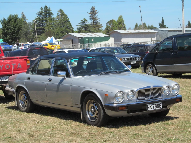 a silver car is parked next to other cars in a field