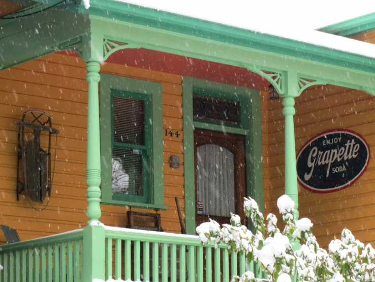 a green and yellow house is covered with snow