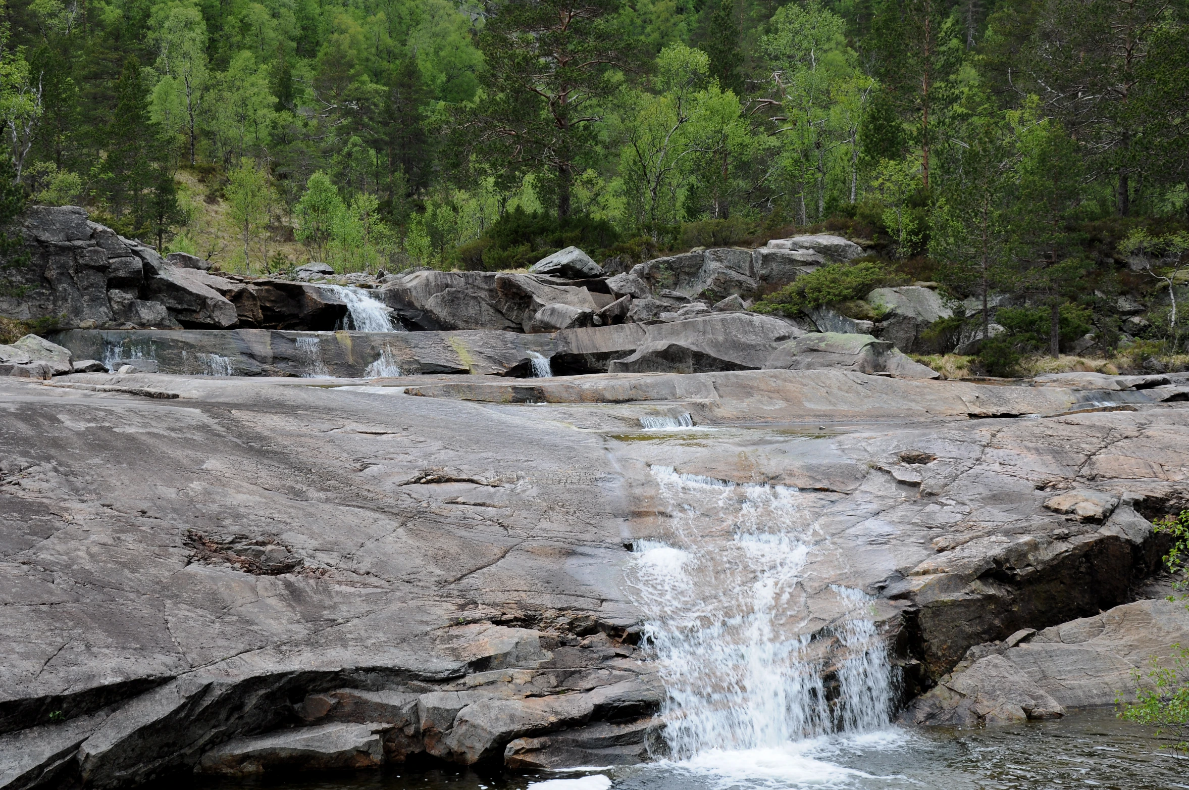 a waterfall is seen in the middle of the rocks