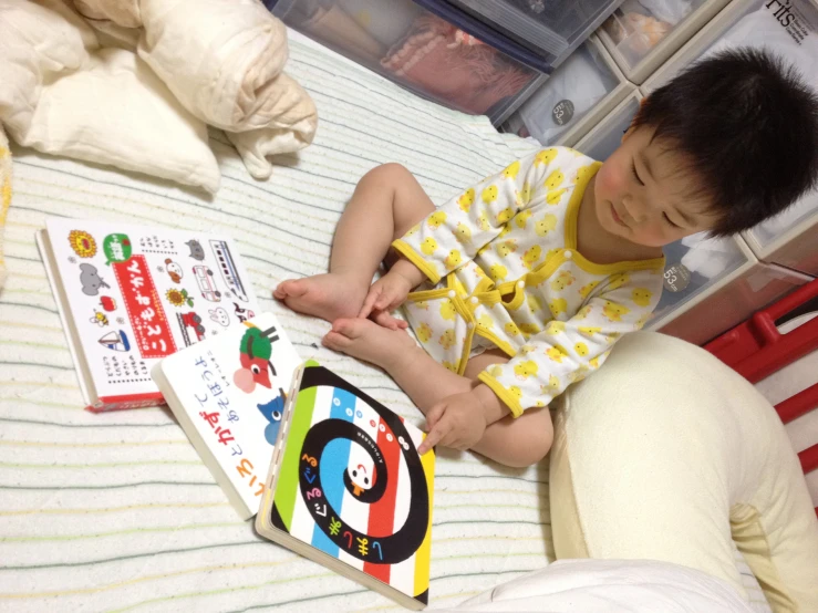 a boy sitting on a bed holding a book