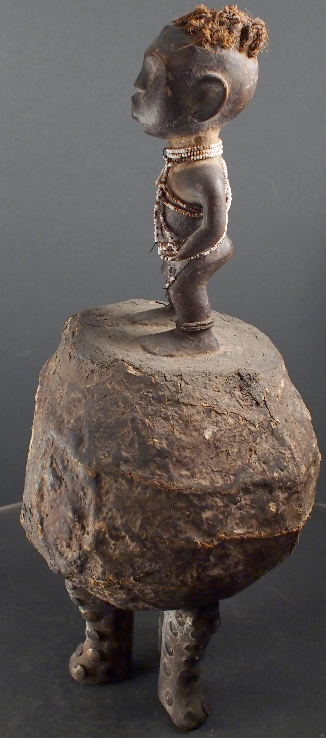 an artistic sculpture of a african man sitting on a rock