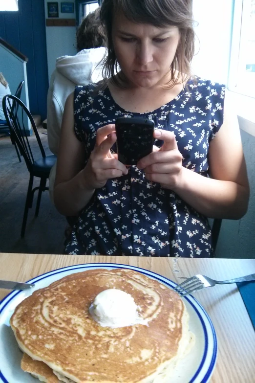 a girl taking a selfie in front of a stack of pancakes