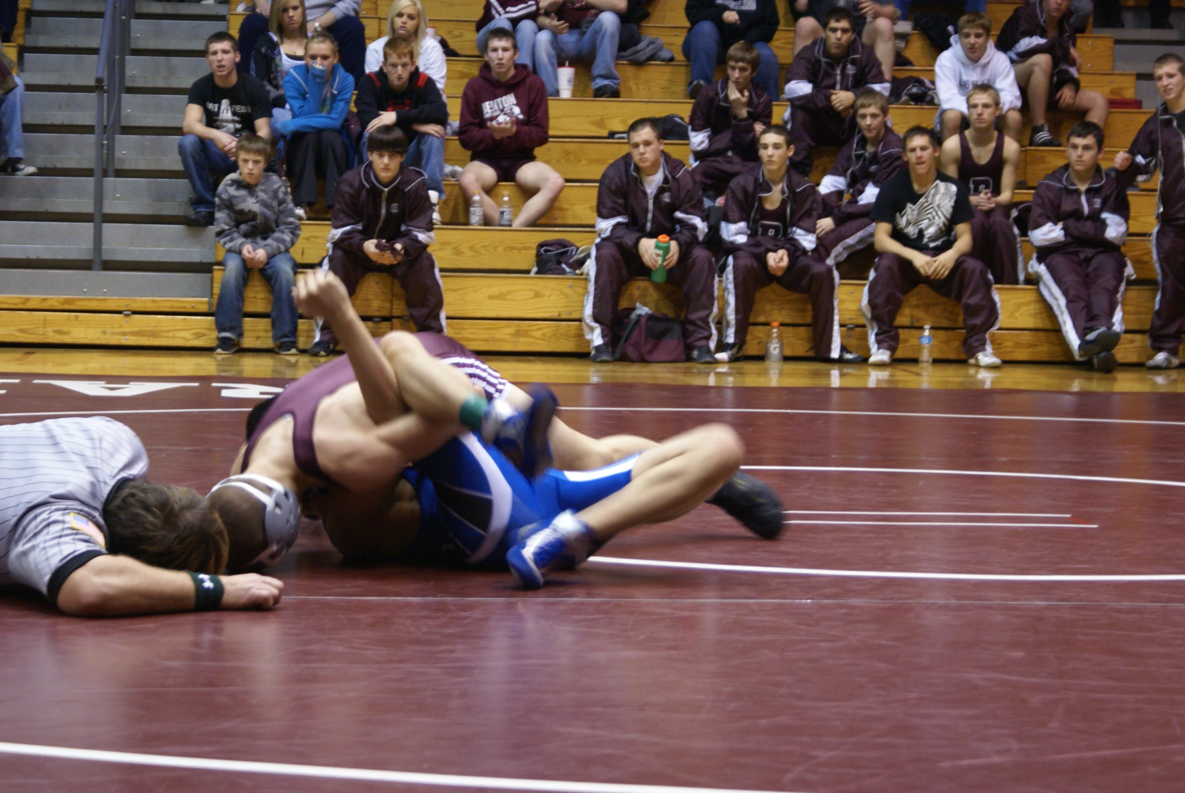 a wrestling match in progress with the crowd watching